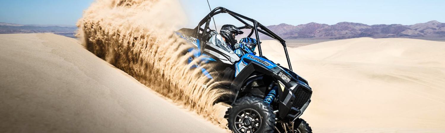 Two people riding on a 2020 Polaris® UTV out in the sand dunes